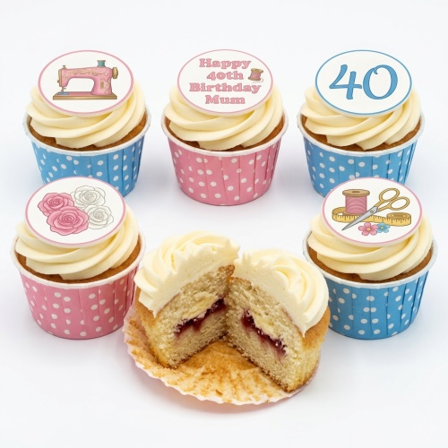 Six cupcakes with white icing, pink and blue polka dot cases, and sewing/floral themed toppers including a sewing machine, scissors, thread, roses, and a custom age.
