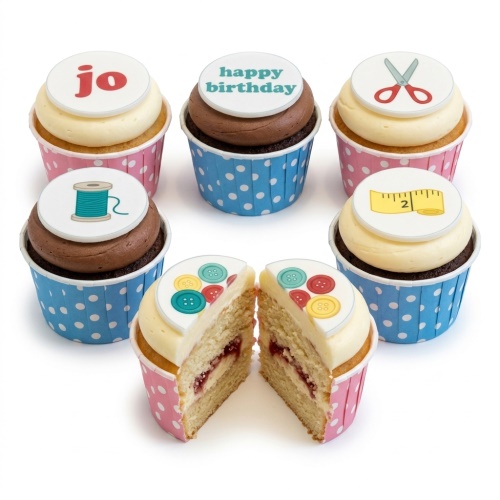 A set of six sewing theme birthday cupcakes with edible toppers featuring scissors, thread, tape measure, and buttons, in pink and blue polka dot cases.
