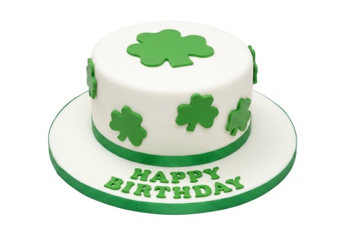 Round white birthday cake decorated with green shamrocks and a "Happy Birthday" message.