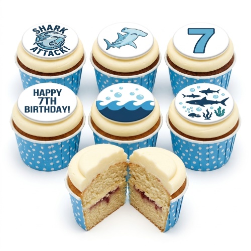 Shark themed birthday cupcakes with various shark and ocean wave toppers, blue polka dot wrappers, and a custom age topper.