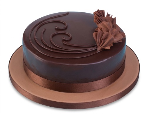 Round chocolate cake with glaze, piped swirls, and ruffled chocolate decorations.