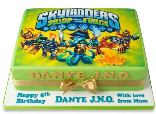 Skylanders Swap Force themed birthday cake with characters and logo, decorated with a gold ribbon.