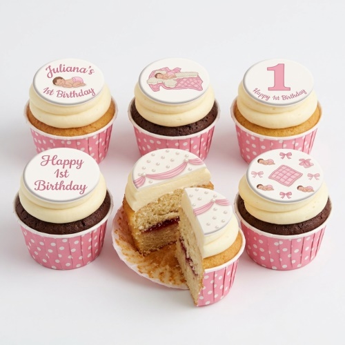 Six pink and white 1st birthday cupcakes for a baby girl, some with sleeping baby toppers and a number one.