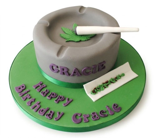 Round grey and green ashtray themed birthday cake with cannabis leaf and rolled joint decorations.