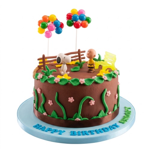 Round brown birthday cake with Snoopy and Charlie Brown figurines, colourful balloons, and green decorations.