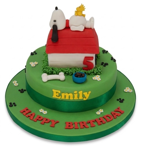 Two-tier green Snoopy and Woodstock birthday cake with red doghouse, custom age, and personalised name.