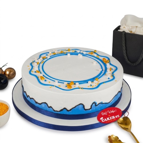 Round white cake with blue wavy piping, gold and white sprinkles, and a blue ribbon base.