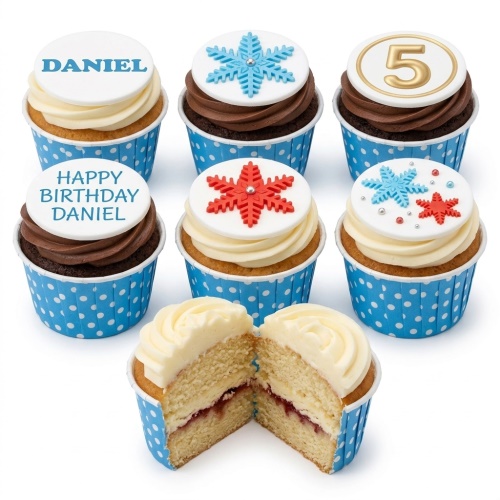 Assortment of vanilla and chocolate cupcakes with blue polka dot wrappers, decorated with white fondant toppers, blue and red snowflakes, and custom age and name.