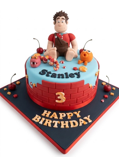 Wreck-It Ralph themed birthday cake with a custom age topper and personalised name, featuring a brick wall design and candy decorations.