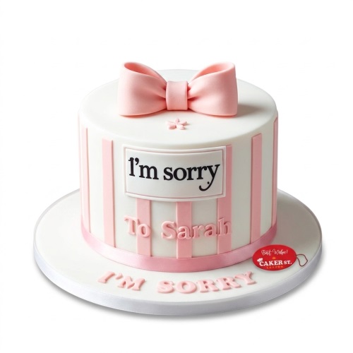 White round sorry cake with pink vertical stripes, a large pink bow on top, and a white plaque with 'I'm sorry' text.
