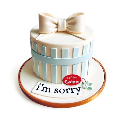 Elegant gift box cake with a cream bow, light blue stripes, and a custom message plaque.