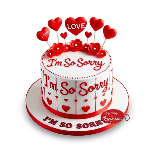 White round cake with red 'I'm So Sorry' message and red heart decorations with 'LOVE' on some.