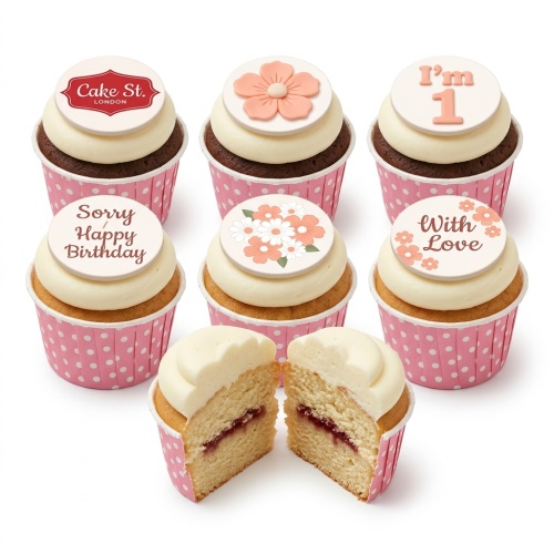 Assortment of floral themed birthday cupcakes with white frosting and pink polka dot cases, some with custom messages.
