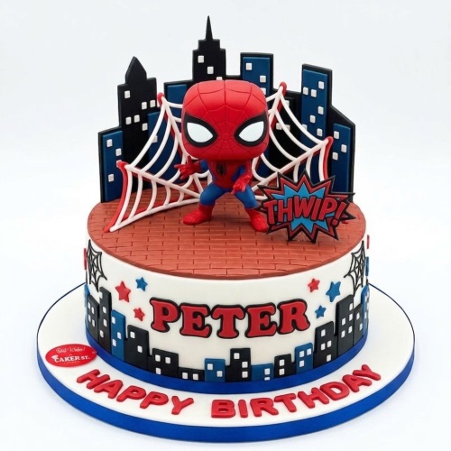 Round Spiderman themed birthday cake with a Spiderman figure, city skyline, and spider web decorations.