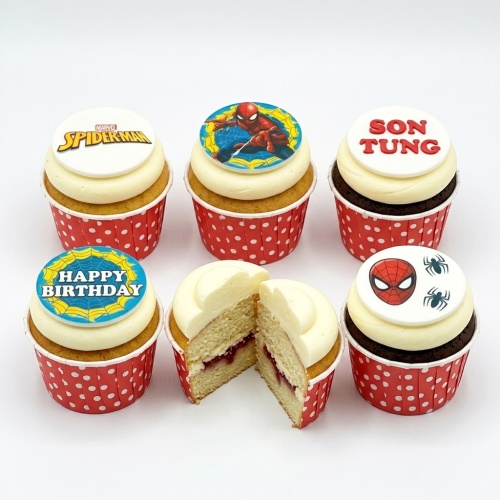 Spiderman themed cupcakes with edible toppers, red polka dot wrappers, and white frosting.