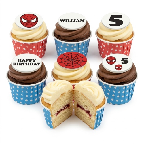 Six Spiderman themed cupcakes with red and blue polka dot cases, some with Spiderman mask and web toppers, one with a custom age '5', one with a custom name 'WILLIAM', and one with 'HAPPY BIRTHDAY'. One cupcake is cut open revealing jam filling.