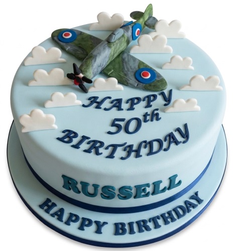 Round light blue fondant cake with a green Spitfire airplane model and white clouds.