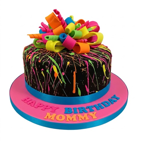 Round black cake with neon splatter paint design and colourful curled ribbon topper on a pink board with "Happy Birthday Mommy" message.