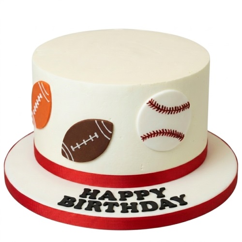 Round white birthday cake with edible American footballs and baseballs, and a red ribbon.