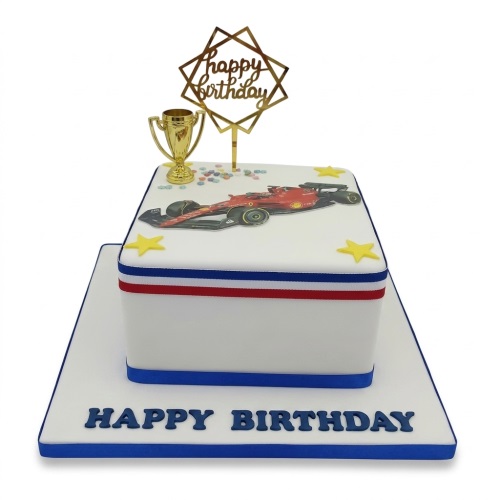 White rectangular birthday cake with a red Formula 1 car, gold trophy, yellow stars, and a 'Happy Birthday' topper.