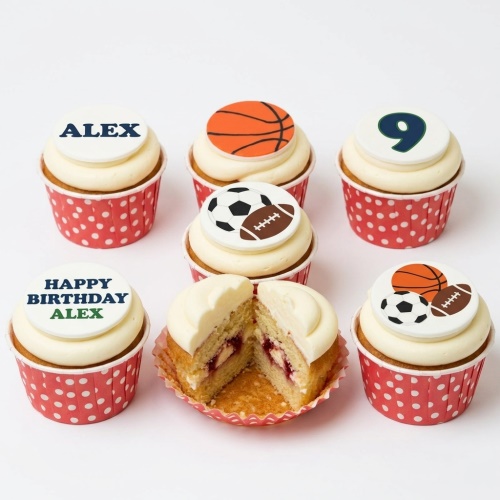 Six sports theme birthday cupcakes with white frosting, red polka dot wrappers, and edible sports ball toppers, including a custom age and name example.