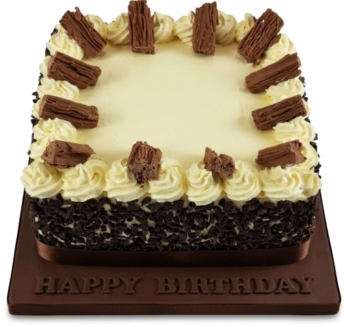 Square birthday cake with cream icing, chocolate shavings on sides, and chocolate flakes on top.