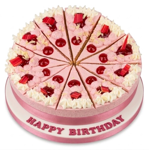 Round pink birthday cake with cream swirls, red fruit, and pre-sliced portions on a white board with 'Happy Birthday' text.