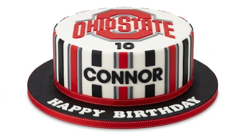Round white sports theme birthday cake with red, black, grey stripes and a logo on top.