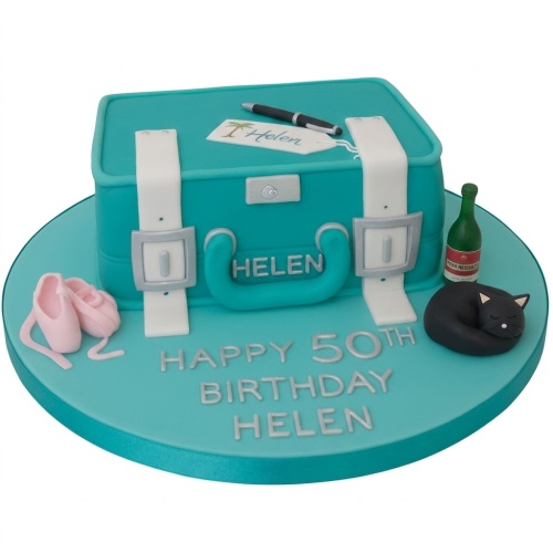 Teal suitcase birthday cake with white straps, ballet shoes, sleeping cat, champagne bottle, and custom age text.