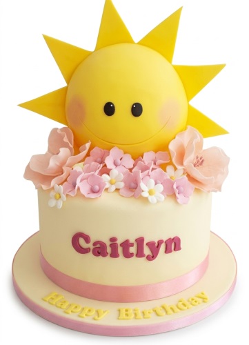 Round yellow birthday cake with a smiling sun topper, pink and white sugar flowers, and a pink ribbon.