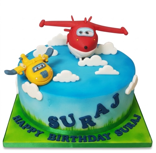 Round blue and green aeroplane theme birthday cake with red and yellow cartoon planes and white clouds.