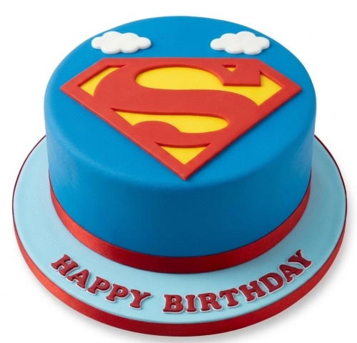 Round Superman logo birthday cake with blue fondant, red and yellow 'S' shield, white clouds, and red ribbon.