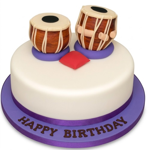 Round white birthday cake with two edible tabla drums and a red cushion on top, purple ribbon and board with a custom message.