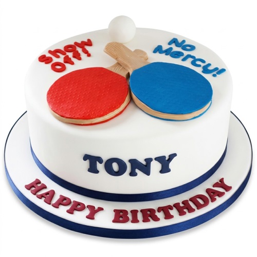 White round cake with red and blue table tennis paddles, a white ball, and a navy ribbon.