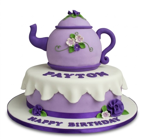 Two-tier purple and white teapot birthday cake with sugar flowers and custom name.
