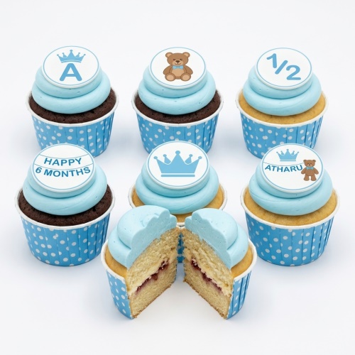 Baby boy half birthday cupcakes with blue frosting, teddy bear, crown, and custom initial toppers.