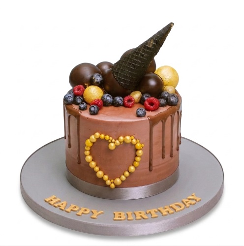 Round chocolate drip birthday cake with berries, gold spheres, and a black cone on a grey board.