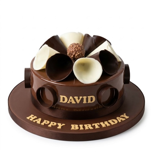 Round chocolate birthday cake with white and dark chocolate curls, a chocolate truffle, and gold "Happy Birthday" message.