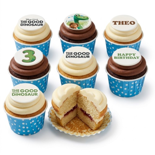 A selection of The Good Dinosaur themed birthday cupcakes with Arlo, Spot, movie logo, and a custom age '3' topper, in blue polka dot wrappers.