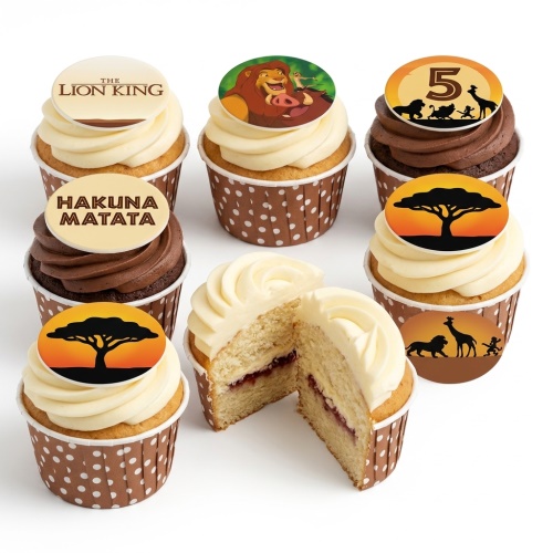 A selection of Lion King themed cupcakes with edible toppers featuring Simba, Pumbaa, Hakuna Matata, and a sunset silhouette. One cupcake has a '5' topper. Cupcakes have white and chocolate frosting.