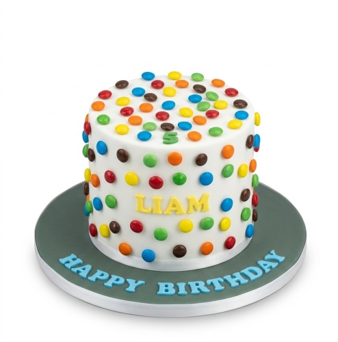 White round cake covered in colourful chocolate buttons with 'Happy Birthday' message.
