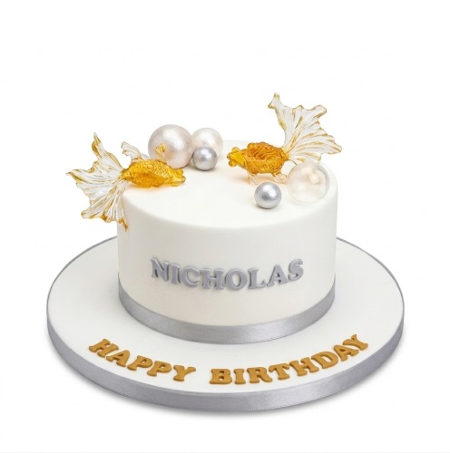White birthday cake with edible goldfish, silver and pearlescent spheres, and a silver ribbon. Personalised with a name.