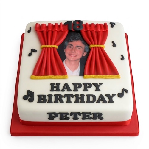 White square cake with red stage curtains, a custom photo, music notes, and a custom age topper.