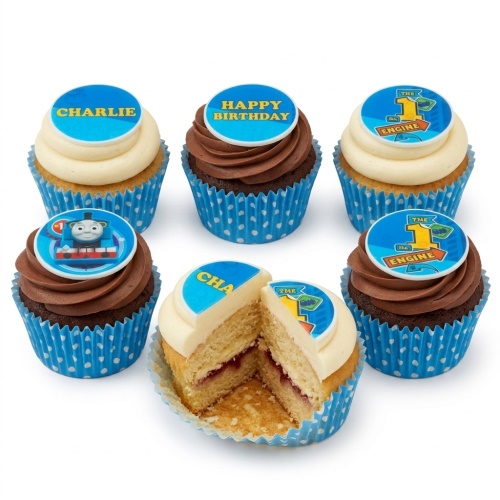 Thomas The Tank Engine themed birthday cupcakes with chocolate and vanilla frosting, blue polka dot cases, and edible toppers featuring Thomas, "The 1st Engine", "Happy Birthday", and a custom name example.