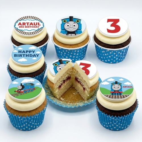Thomas the Tank Engine themed birthday cupcakes with blue wrappers, white frosting, and edible toppers.