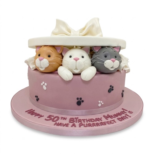 Round pink birthday cake with three fondant cats peeking from a gift box and paw prints.