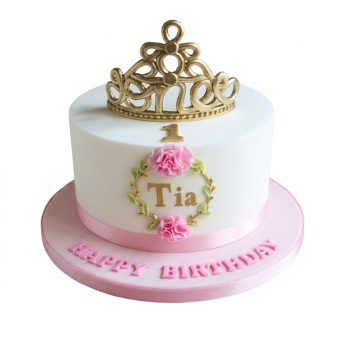 White round cake with gold tiara topper, gold number one, and a floral wreath with pink flowers and a personalised name.