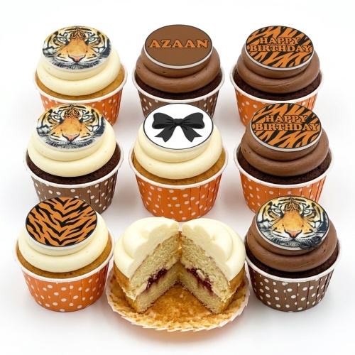 Set of tiger themed birthday cupcakes with tiger face, tiger stripe, black bow, and 'Happy Birthday' toppers, in orange and brown cases.