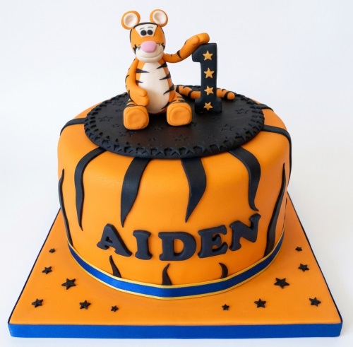 Orange and black Tigger themed birthday cake with a Tigger figurine and custom age topper.