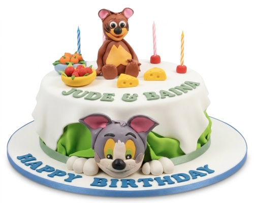 Round white birthday cake with Tom and Jerry figures, cheese, and fruit decorations.
